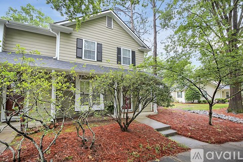 A house with a grey roof and a red mulch garden in front.