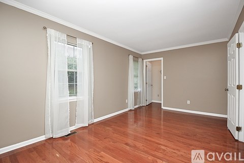 A room with wooden floors and white curtains.