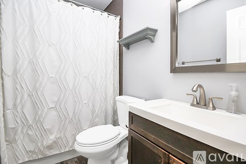 A white toilet in a bathroom with a white shower curtain.
