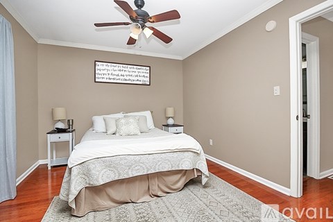 A bedroom with a bed, a ceiling fan, and a framed picture on the wall.