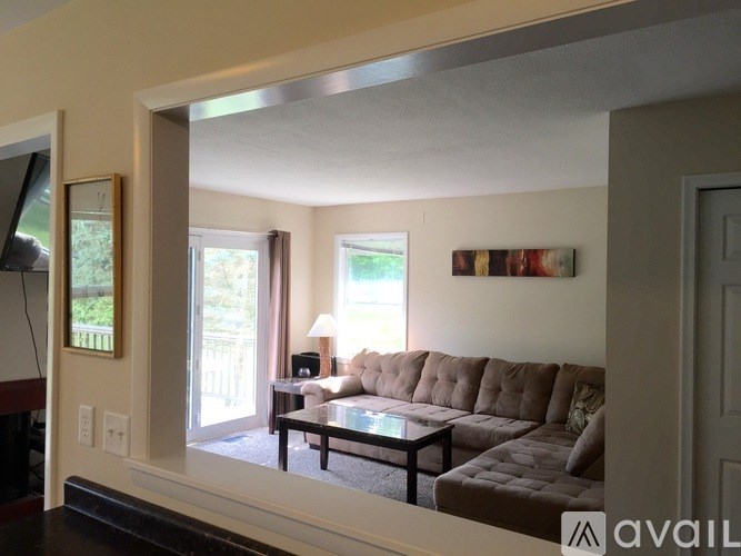 A living room with a brown couch and a glass table.