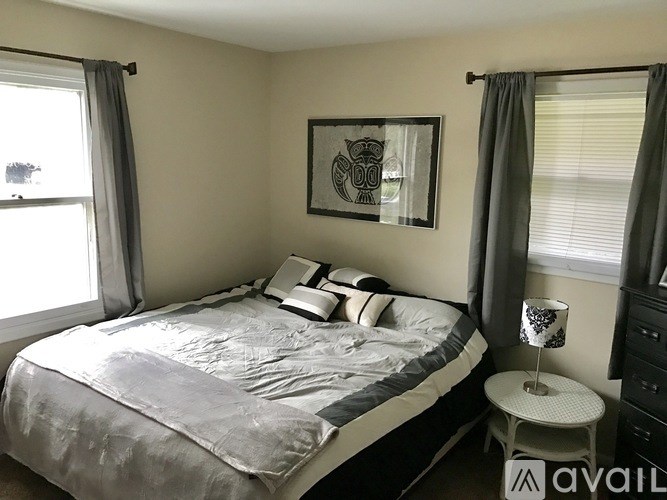 A bedroom with a bed, nightstand, and a picture on the wall.