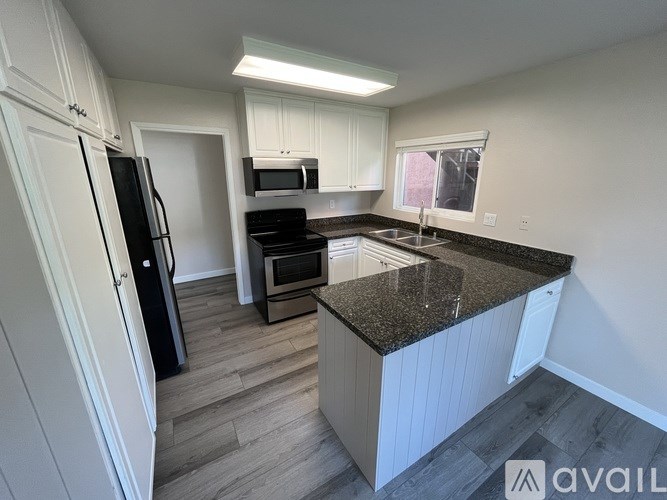 A kitchen with a black fridge and a granite counter top.