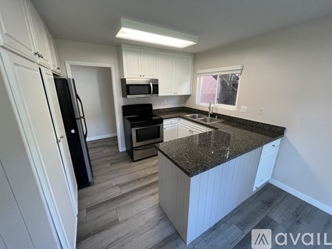 A kitchen with a black fridge and a granite counter top.