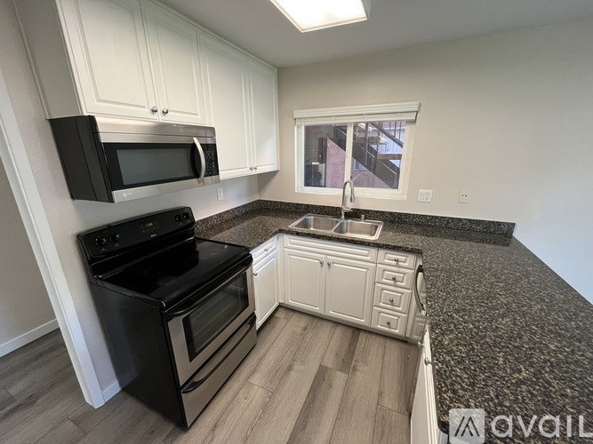 A kitchen with black appliances and white cabinets.