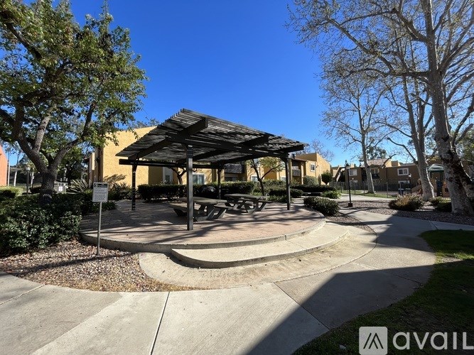 A pavilion with a roof and a circular walkway in front of it.
