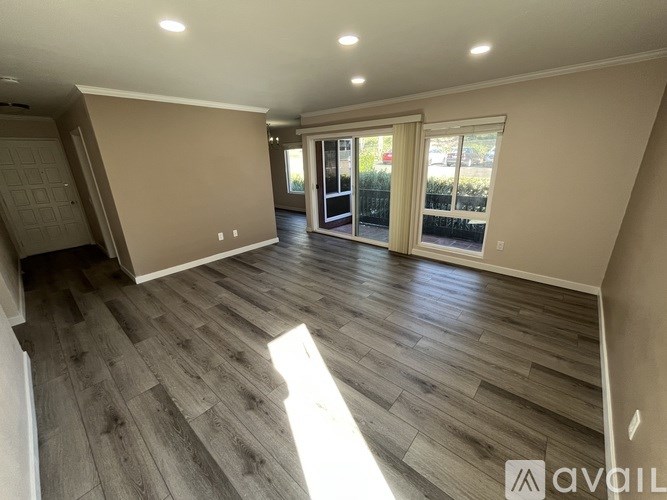 A spacious room with wood flooring and a large window.