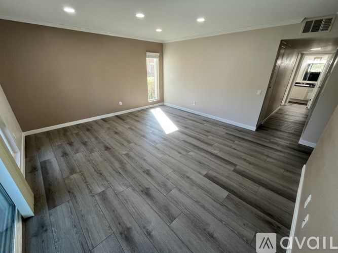 A spacious room with wooden flooring and a doorway leading to another room.