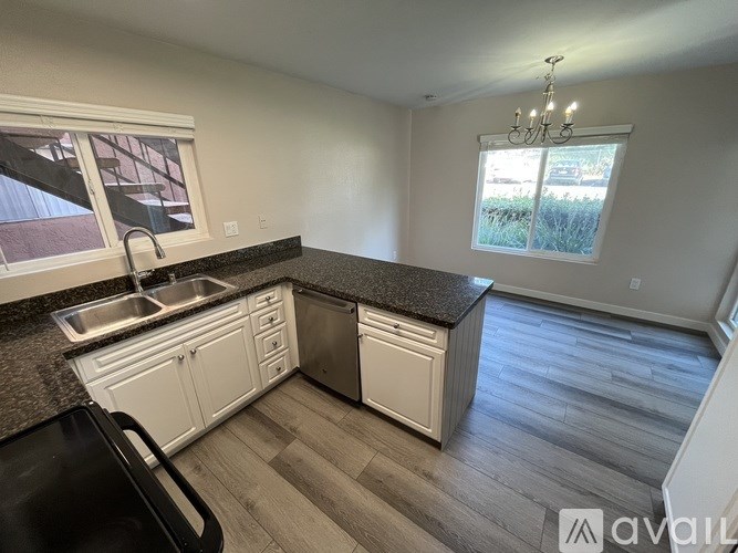 A kitchen with a sink, dishwasher, and a window.