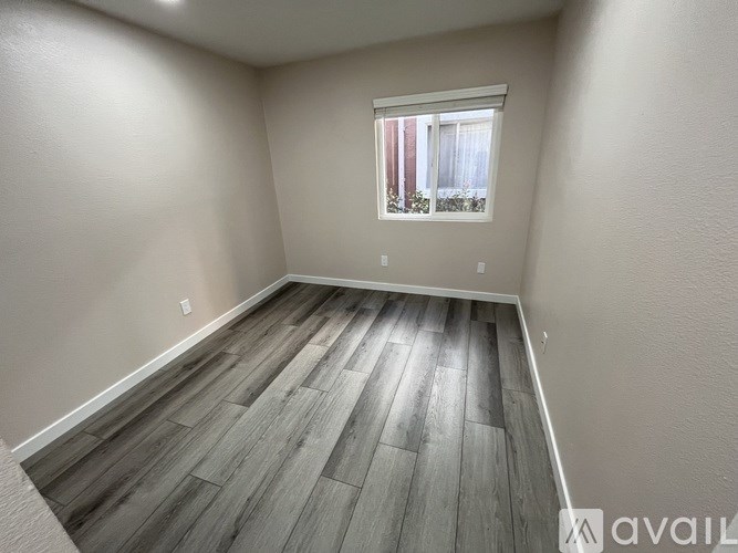 A room with wooden flooring and a window with blinds.