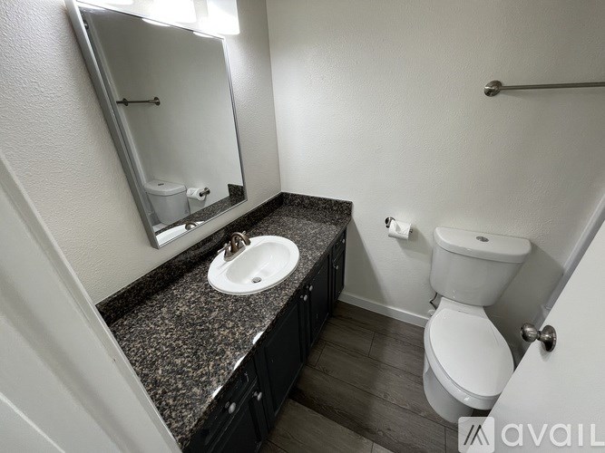 A bathroom with a granite countertop and a white toilet.