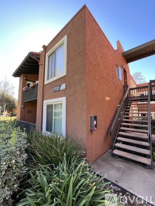 A red brick house with a staircase leading to the entrance.