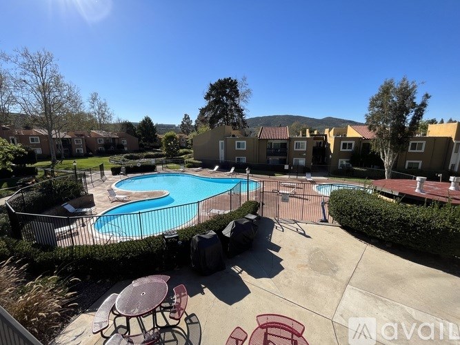 A sunny day at the pool with tables and chairs.