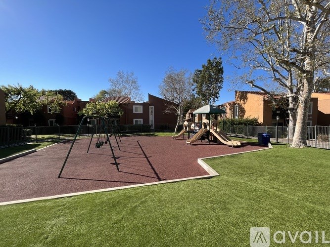 A playground with swings and a slide in front of a building.
