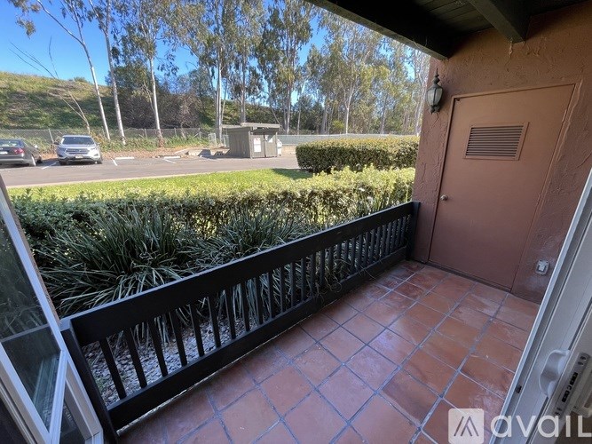 A balcony with a black railing and a brown door.