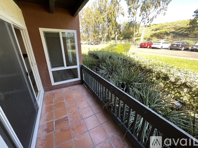 A balcony with a view of a street with cars and a hill in the background.