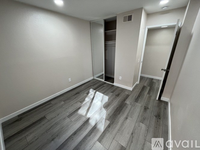 A room with wood flooring and a white wall.