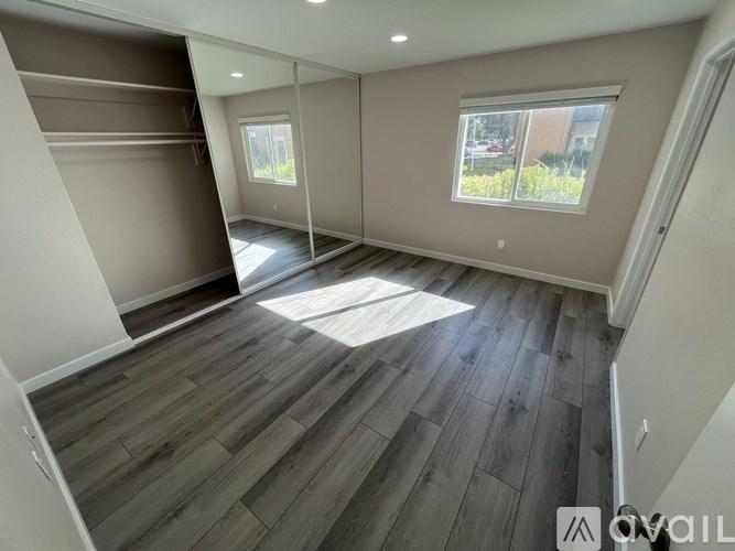 A room with wooden flooring and a window with a view of the outside.