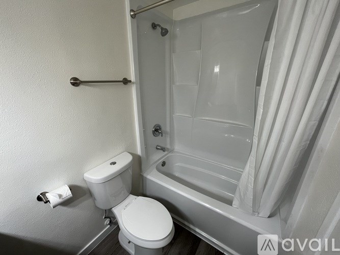 A white toilet sits next to a bathtub in a small bathroom.