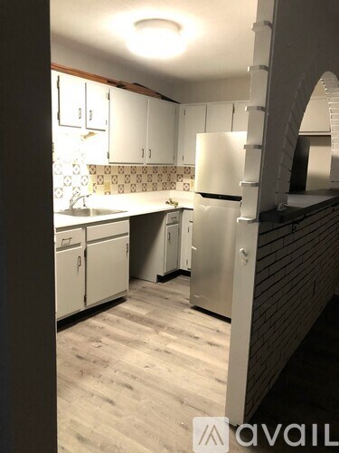 A kitchen with white cabinets and a wooden floor.