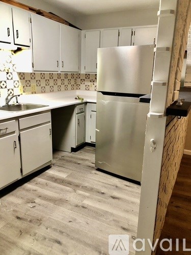 A kitchen with a refrigerator, sink, and cabinets.