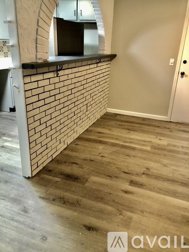 A room with a brick wall and wooden flooring.