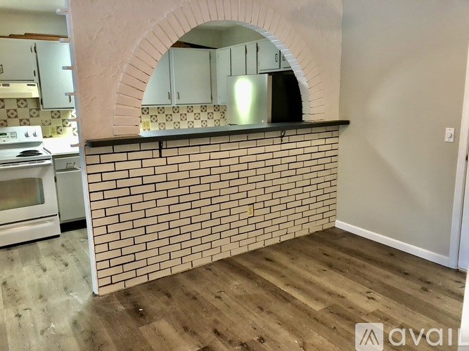 A kitchen with a brick wall and a wooden floor.