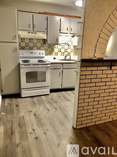 A kitchen with a white stove top oven and white cabinets.