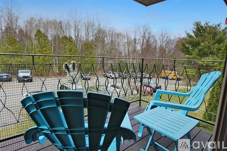 Two blue chairs on a balcony overlooking a parking lot.