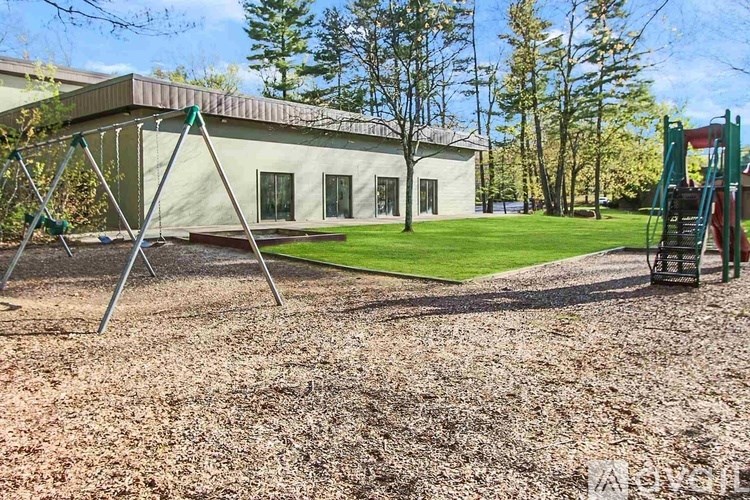 A playground with a swing set and a slide in front of a white building.