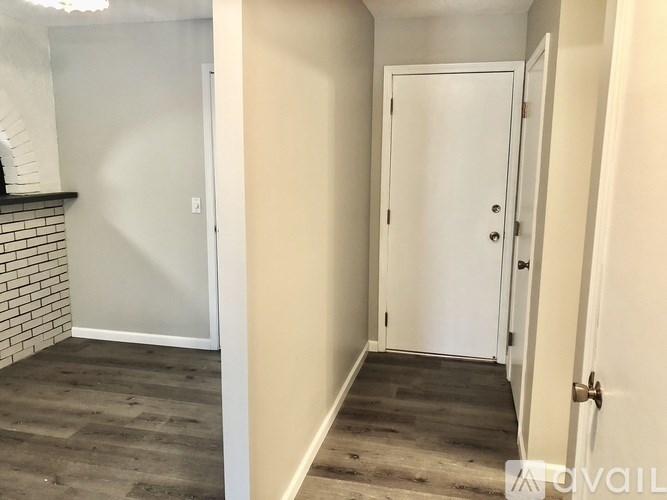 A room with a white door and a brick wall.