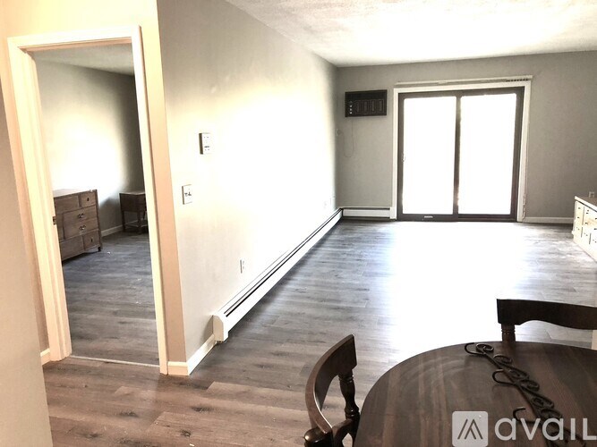 A room with a wooden floor and a dining table with chairs.