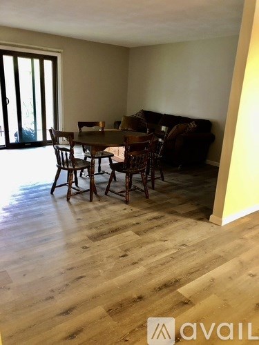A living room with a brown couch and a wooden dining table.