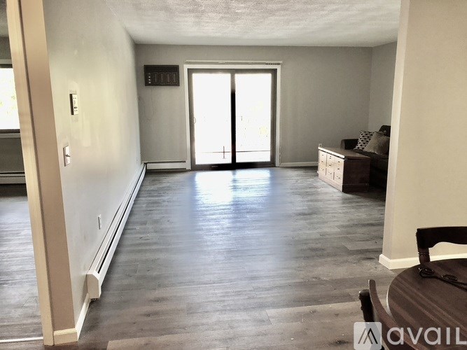 A spacious room with a sliding glass door and a wooden floor.