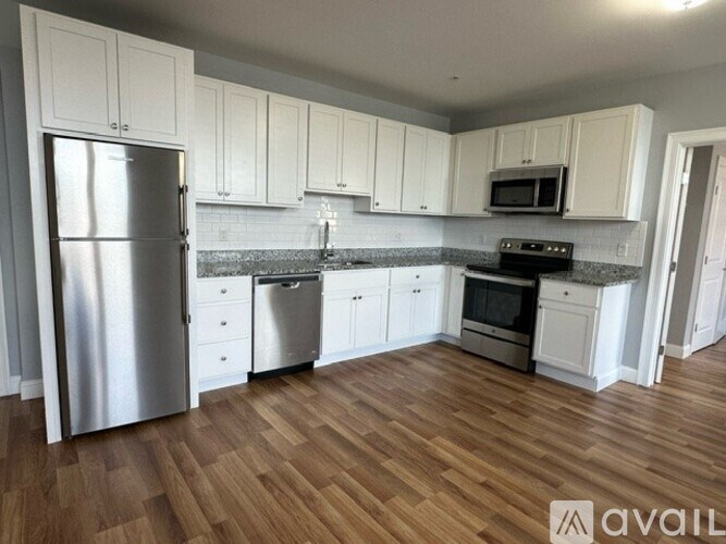 A kitchen with white cabinets and a wooden floor.