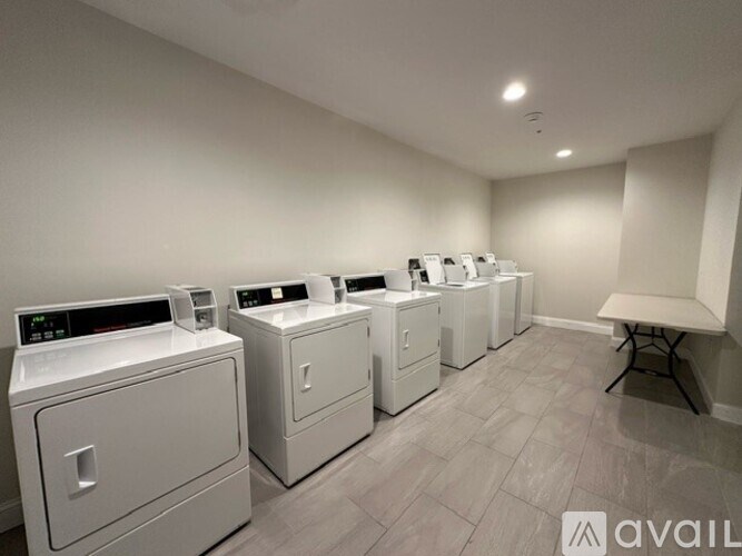 A row of washing machines are lined up in a laundry room.