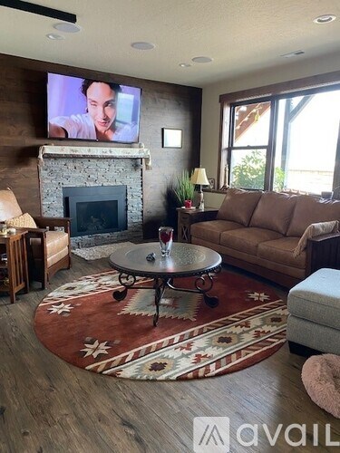 A living room with a fireplace and a television mounted above it.