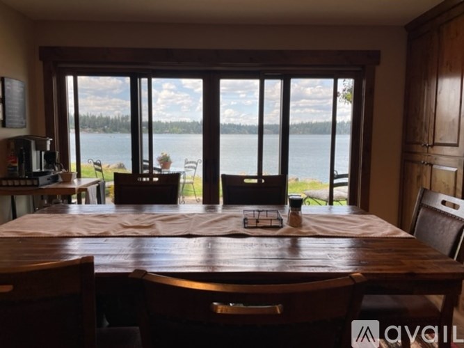 A dining room with a table set for four and a view of a lake through the windows.