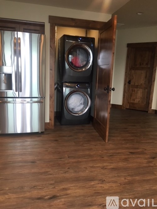 A black washer and dryer stacked on top of each other in a room with wooden floors.