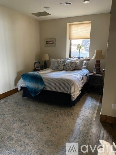 A bedroom with a bed, two lamps, and a window.