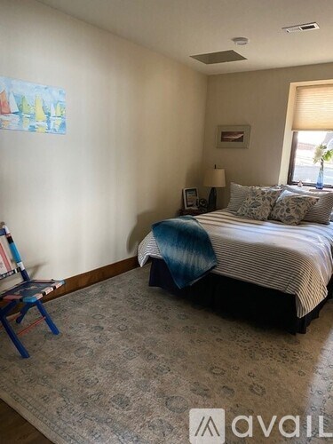 A bedroom with a bed, a chair, and a painting on the wall.