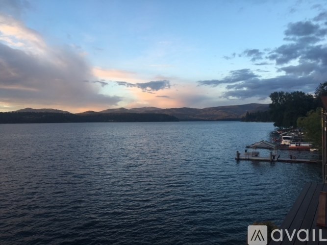 A body of water with boats docked on the side and a mountain in the distance.