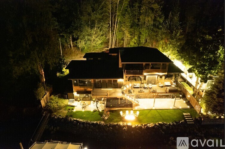 A house is lit up at night with lights on the deck and garden.