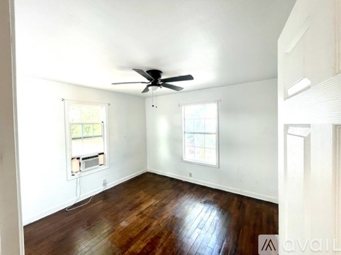 A room with a ceiling fan and two windows.