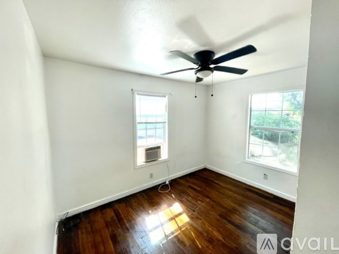 A room with a ceiling fan and two windows.