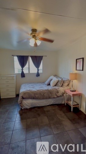 A bedroom with a bed, nightstand, and a ceiling fan.