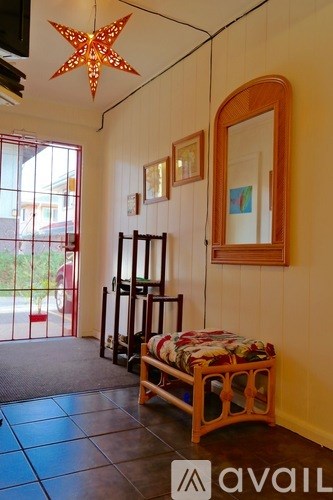 A room with a star-shaped light hanging from the ceiling and a bench with a cushion on it.