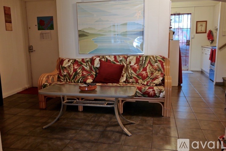 A sofa with a floral pattern sits in a room with a painting on the wall.