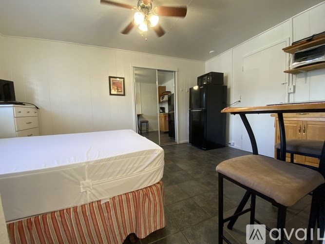 A bedroom with a bed, chair, and a ceiling fan.