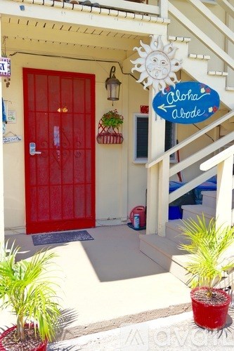 A red door with a sign that says Aloha Above.